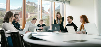 Ideen entwickeln mit Weitblick – moderne Lernräume für kreative Zusammenarbeit Studierendengruppe arbeitet gemeinsam mit Laptops in hellem Seminarraum mit Alpenblick