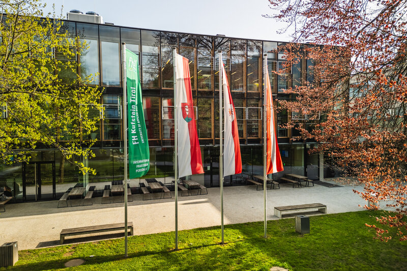 Der Park und das Gebäude der FH Kufstein Tirol mit 4 Flaggen. | © FH Kufstein Tirol