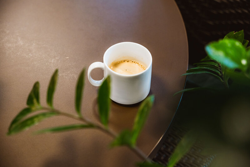 Eine Tasse gefüllt mit Kaffee steht auf einem Holztisch neben einer grünen Pflanze. | © FH Kufstein Tirol