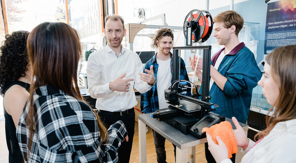 Ein Mann stellt anderen Personen im Raum einen 3D Drucker vor, als Teil eines Workshops. | © FH Kufstein Tirol