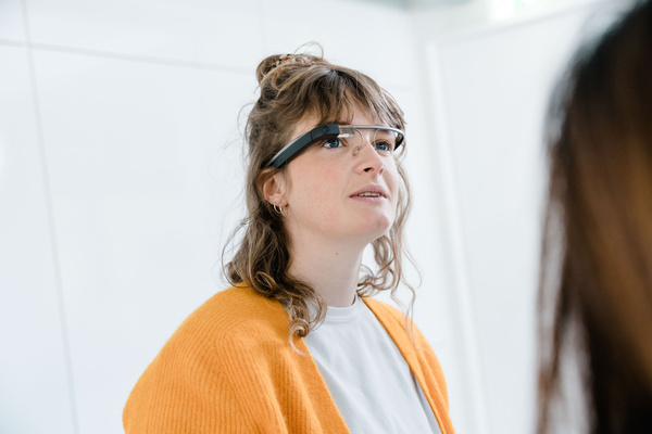 Eine Frau mit brünetten, lockigen Haaren trägt eine Eye-Tracking Brille und schaut leicht nach oben. | © FH Kufstein Tirol