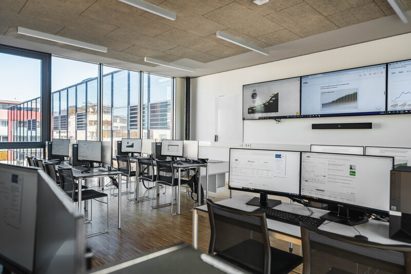 Ein lichtdurchfluteter Computerraum mit Monitoren und Computerarbeitsplätzen; aus den Fenster sieht man ein weiteres Gebäude | © FH Kufstein Tirol