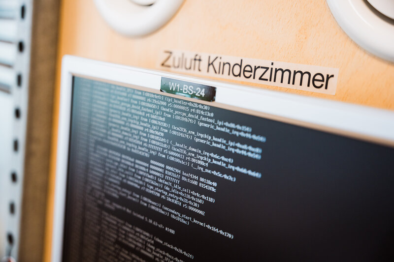 Unter dem Schriftzug "Zuluft Kinderzimmer" wird ein Bildschirm mit vielen Code-Textzeilen gezeigt. | © FH Kufstein Tirol