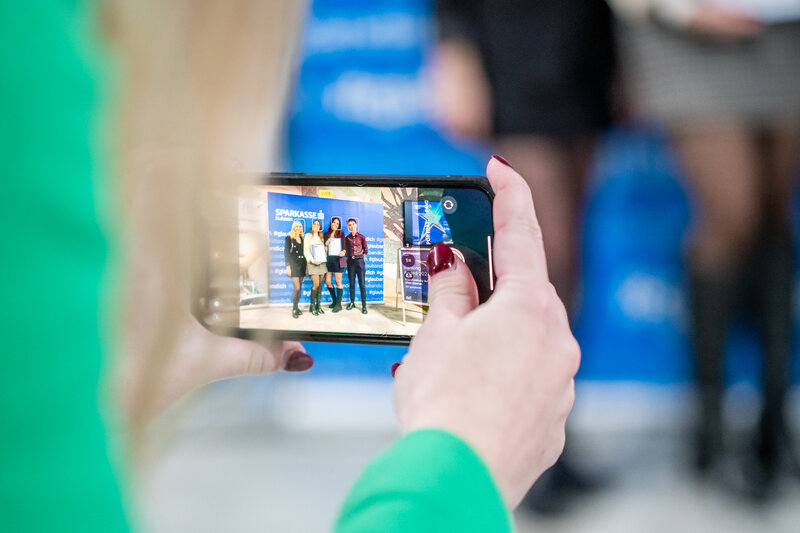 Frauenhände, die ein Mobiltelefon halten, auf dem die Preisträgerinnen des 3. Banking Awards sichtbar sind | © Sparkasse Kufstein.Marco Pircher