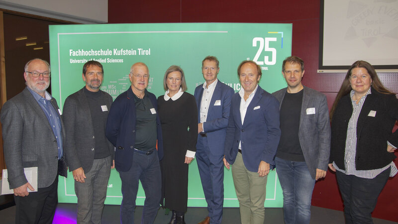 Acht Personen stehen vor einer Leinwand mit dem Text “Fachhochschule Kufstein Tirol University of Applied Sciences” | © FH Kufstein Tirol