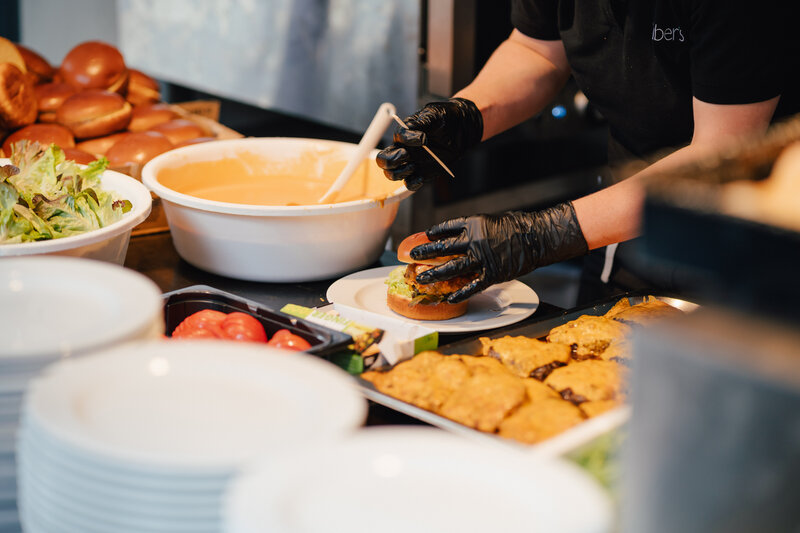 Auf dem Bild ist zu sehen, wie ein Mitarbeiter gerade einen Burger auf dem Homecoming-Event vorbereitet. | © FH Kufstein Tirol