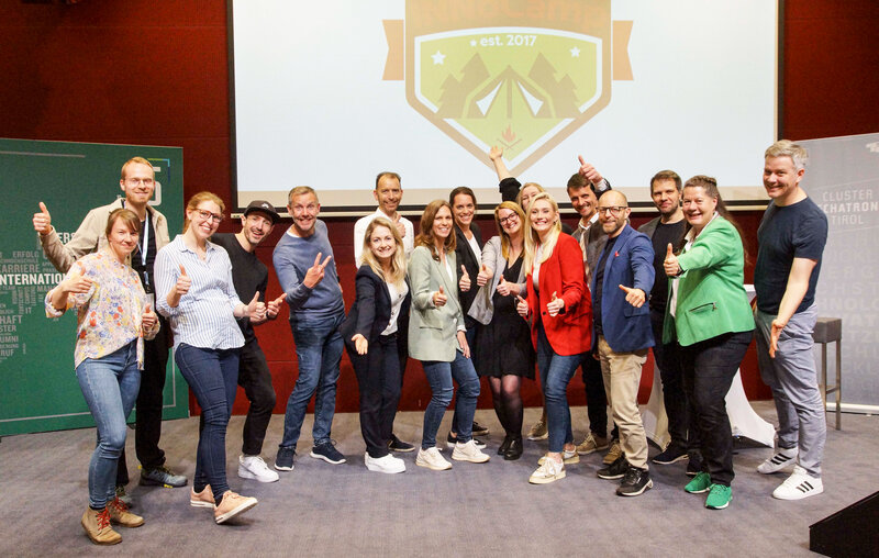 Zu sehen ist das Jurorenteam des INNoCamp. Sie stehen gemeinsam auf einer Bühne. Im Hintergrund befindet sich eine Leinwand mit dem INNoCamp-Logo. | © FH Kufstein Tirol