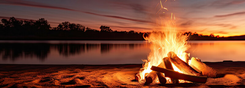 Lagerfeuer am See bei Abenddämmerung. | © AdobeStock.Thares2020