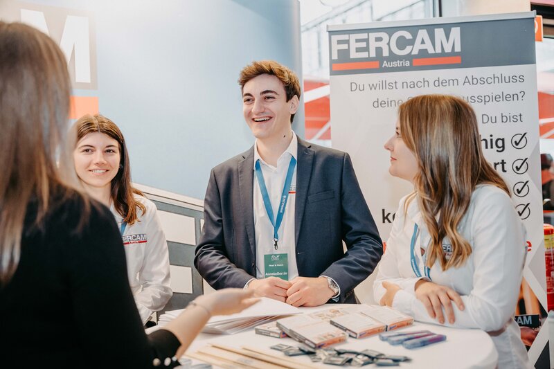 Vier junge Erwachsene stehen an einem Messestand von FERCAM Austria und unterhalten sich  | © FH Kufstein Tirol