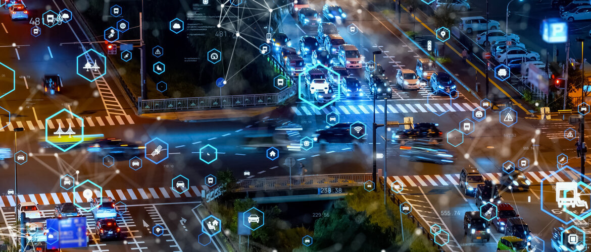 Eine städtische Straße bei Nacht mit Autos und digitalen Symbolen, die intelligente Stadttechnologie darstellen. | © AdobeStock.metamorworks