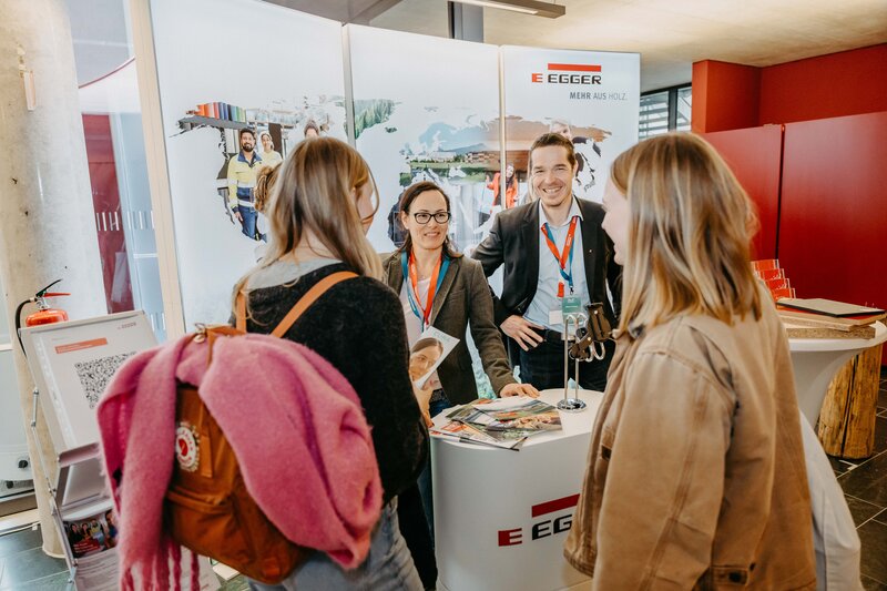 Egger-Stand auf der Meet & Match 2024 der FH Kufstein Tirol mit Standbetreuer:innen und Besucher:innen.  | © FH Kufstein Tirol