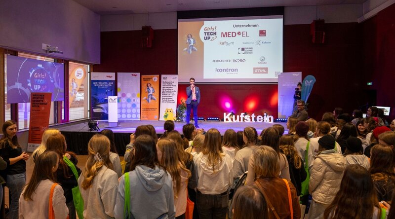 Auftakt zum Girls! TECH UP Day an der FH Kufstein Tirol. Das Foto zeigt den Besucher:innen im Festsaal sowie einen Speaker am Podium.  | © OVE