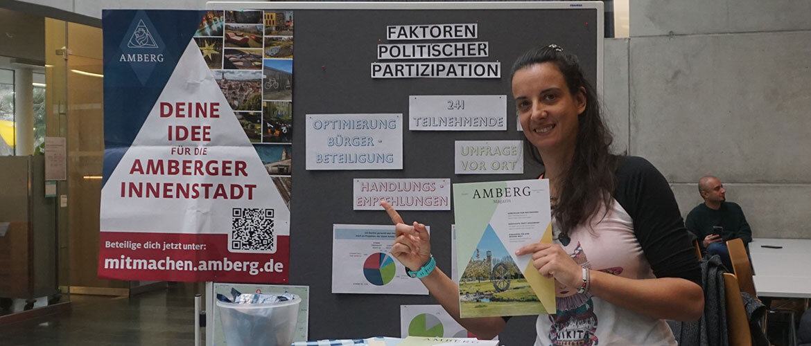 Eine Studentin präsentiert ihre Ergebnisse auf einer Plakatwand in der Aula der FH Kufstein Tirol.