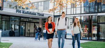 Drei Personen gehen vom Eingang der FH Kufstein Tirol über den Steinpfad in Richtung Stadtpark. | © FH Kufstein Tirol