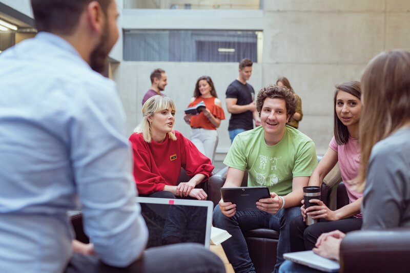 Eine Gruppe sitzt in einem Stuhlkreis in der Aula, und bespricht etwas miteinander. | © FH Kufstein Tirol