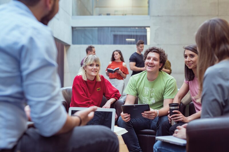 Eine Gruppe sitzt in einem Stuhlkreis in der Aula, und bespricht etwas miteinander. | © FH Kufstein Tirol