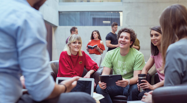 Eine Gruppe sitzt in einem Stuhlkreis in der Aula, und bespricht etwas miteinander. | © FH Kufstein Tirol