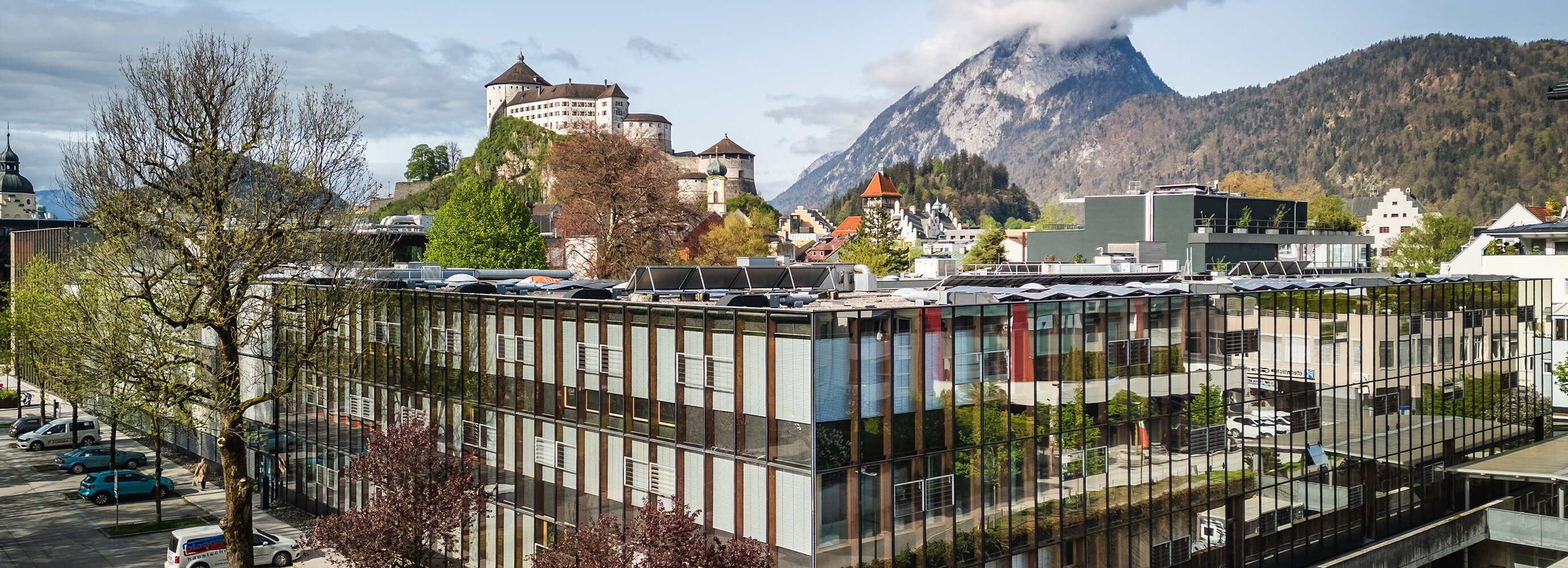 FH Kufstein Tirol von der Straßenseite, hinter welcher man in der Ferne die Festung Kufstein sieht. | © FH Kufstein Tirol