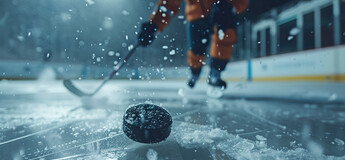 Ein Eishockeyspieler ist in Bewegung, während ein Puck auf dem Eis liegt. | © AdobeStock.VagnerCastro