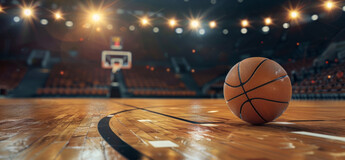 Ein Basketball liegt auf einem beleuchteten Basketballfeld | © AdobeStock.Arianne