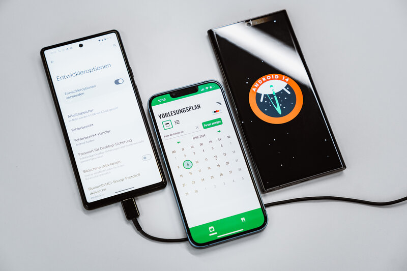 Web_Lab_Mobile_Apps Drei Smartphones zeigen etwas auf ihren Bildschirmen. Das linke zeigt Entwickleroptionen, das mittige zeigt die Übersicht der FH-App, und das Rechte zeigt eine Grafik.