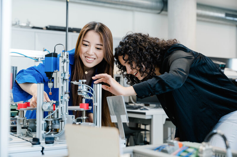 Automation_Lab_3D_Drucker_Demonstration Zwei Frauen untersuchen die Ergebnisse eines 3D Drucks.