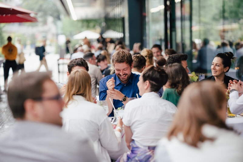 Eine große Gruppe von Personen unterhält sich und lacht beim Homecoming-Event im Außenbereich. | © FH Kufstein Tirol