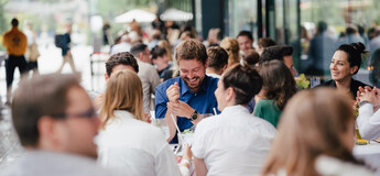 Eine große Gruppe von Personen unterhält sich und lacht beim Homecoming-Event im Außenbereich. | © FH Kufstein Tirol