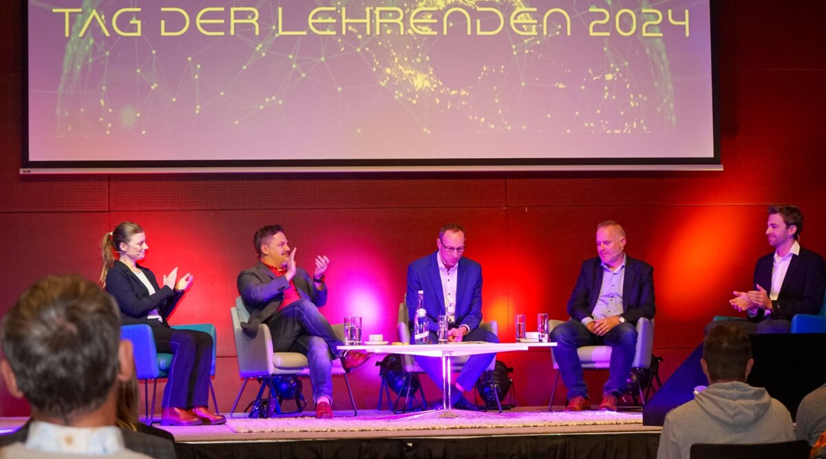 Tag-der-Lehrenden-Podium-Diskussion Diskussion auf dem Podium beim Tag der Lehrenden im Festsaal der FH Kufstein Tirol. Expert:innen sprechen über virtuelle Realität in der Bildung.